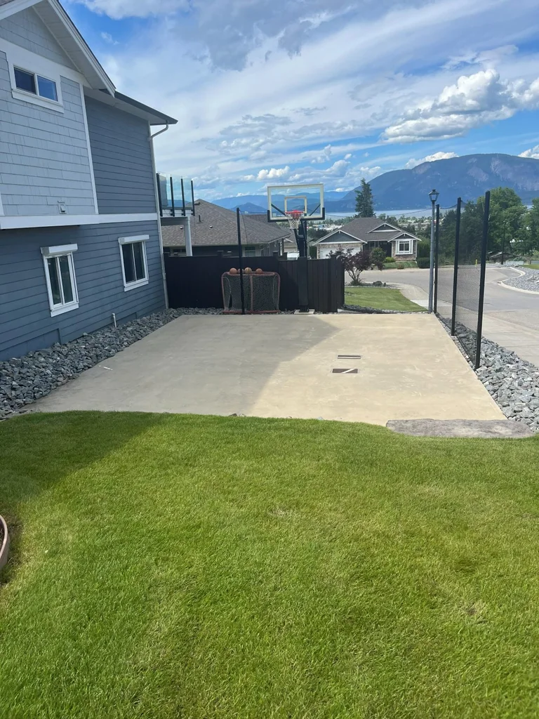 Bare concrete pad beside the house before court tiles are installed